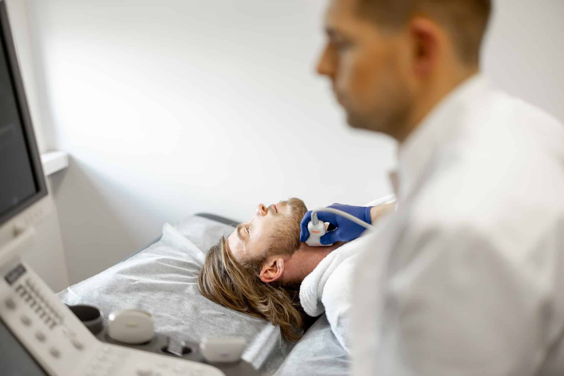 Young guy during an ultrasound diagnosis of the carotid artery. Concept of ultrasound diagnostics and men's health. Idea of examination of cardiovascular diseases