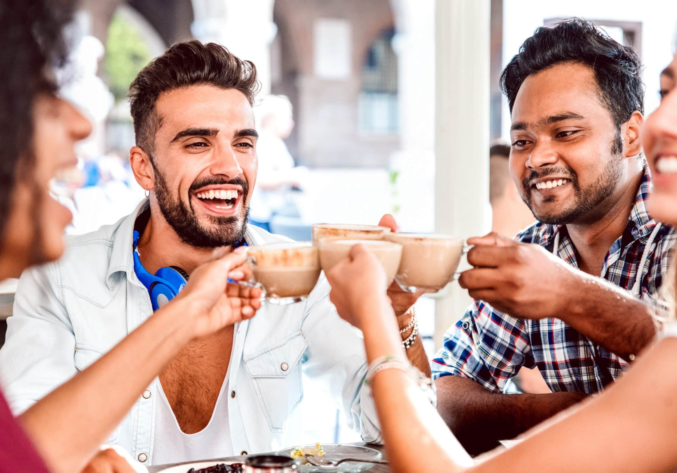 People group drinking latte at coffee bar restaurant - Happy friends talking and having fun together at cafeteria dehors - Life style concept with happy men and women at cafe - Focus on left guy